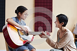 Teacher teaching student to play guitar