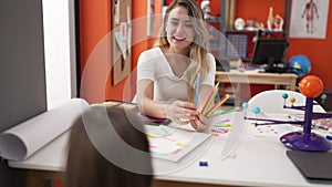 Teacher and toddler having planets lesson holding color pencils at classroom