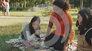 Teacher tuning microscope, showing nature object to girls outdoors