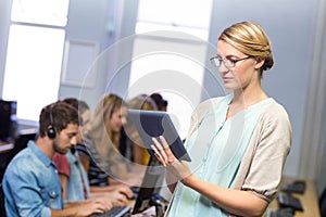 Teacher using digital tablet in computer class