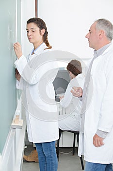 Teacher watching student write on chalkboard