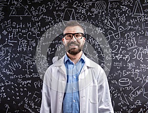 Teacher in white coat and eyeglasses against big blackboard wit