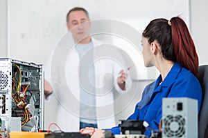 Teacher at whiteboard student with dismantled computer