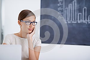 Teacher, woman and laptop by blackboard with thinking in classroom, smile and planning with idea. Person, computer and