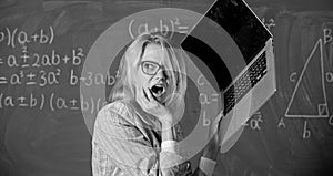 Teacher woman raising laptop above herself ready to destroy. Working conditions of teachers causes nervous disease