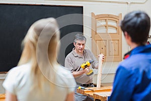 Teacher of a woodwork class teaching two students