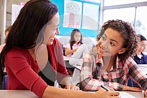 Teacher working with elementary school girl at her desk