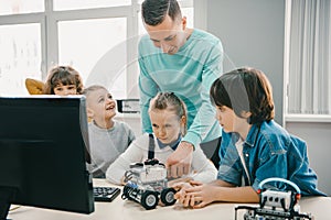 teacher working with teen students on diy robot on stem