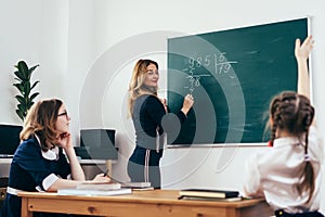 Teacher writes a mathematical example on the blackboard