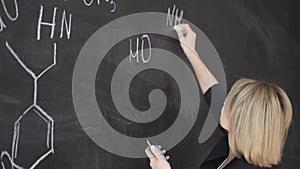 Teacher writing formulas on the chalk Board and explains the students the formula.