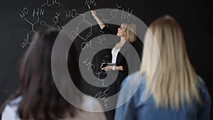 Teacher writing formulas on the chalk Board and explains the students the formula.