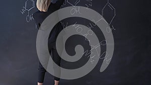 Teacher writing formulas on the chalk Board and explains the students the formula.