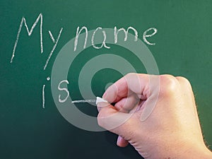 Teacher writing on green chalkboard