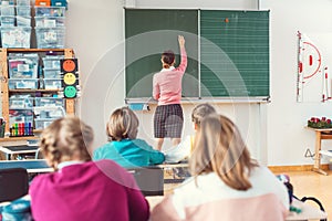 Teacher writing interesting things on blackboard in school