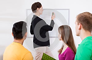 Teacher writing on whiteboard at classroom