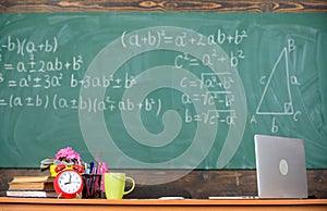 Teachers attributes. Table with school supplies alarm clock books and mug classroom chalkboard background. Working