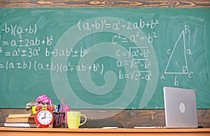 Teachers attributes. Table with school supplies alarm clock books and mug classroom chalkboard background. Working