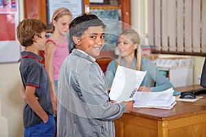 Teachers going to be impressed with my work. a little boy on his way to the teachers desk with his classwork.