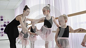 Teachers show how to dance to little ballerinas. Girl dancer in ballet school learns to dance. Young ballerinas jumping