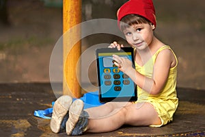 Teaching a child to count on a tablet computer. A little girl holds a tablet in cookies and shows the number 1 on the touch screen