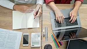 Teaching helping technology concept. Woman young teacher or tutor with adult students in classroom at desk with papers, laptop