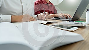 Teaching helping technology concept. Woman young teacher or tutor with adult students in classroom at desk with papers, laptop
