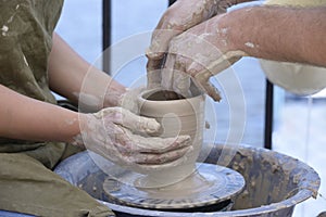 Teaching of wheel throwing. Potter hand correcting woman s ones during shaping clay blank on a potter& x27;s wheel