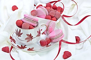 Teacup full of raspberry with macaroon on top and aside