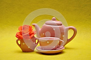 A teacup and a kettle with an orange rose