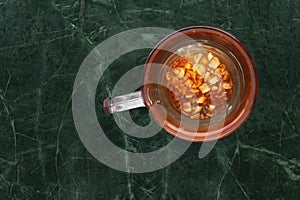 Teaglass with yellowhead root tea in a green marble background