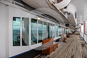 Teak bench and teak lined Promenade Deck of modern cruise ship on a grey stormy day