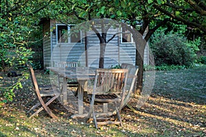 Teak garden furniture in the private garden on wooden hut background