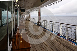Teak lined Promenade Deck of modern cruise ship on a grey stormy day