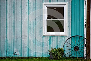 Teal barn with wagon wheel window and flower kettle planter hole in siding