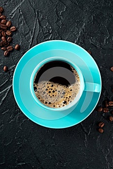 Teal coffee cup and coffee beans, top shot on a black background
