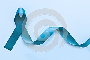 Teal color ribbon bow on blue isolated background with copy space. Ovarian Cancer Awareness, Gynecological, Uterine Cancer, Vulvar photo