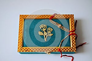 Teal and golden coloured dry fruit box with rakhis. white background. Hindu festival