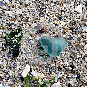 Teal heart sea glass on the beach. Beachcombing on sea shore.a shore. Beach walk