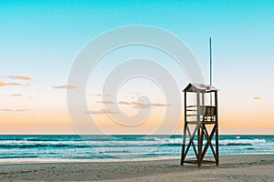 Teal and orange mood of Beach sunrise with vintage lifeguard wooden tower