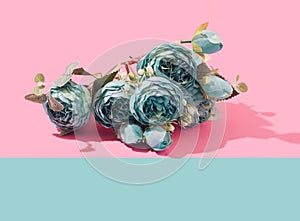 Teal Peonia artificial flowers bouquet on a two tone pastel background. photo