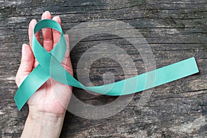 Teal ribbon awareness on woman\'s hand for Ovarian Cancer, Polycystic Ovary Syndrome (PCOS) disease