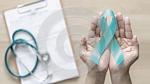 Teal ribbon awareness on woman`s hand for Ovarian Cancer, Polycystic Ovary Syndrome PCOS disease, Post Traumatic Stress Disorder photo