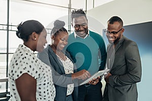 Team of african business people standing and smiling and laughing while using a tablet