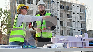 Team architect and builder talking and holding laptop looking model house at construction site, contractor and worker discussion