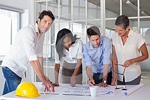 Team of architects going over blueprints with one smiling at camera