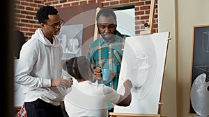 Team of art class students using pencil to draw vase model