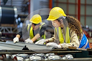 Team of Asian industrial worker is checking the setup value of metal sheet roll forming machine inside roof factory for safety