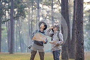 Team of the Asian naturalist looking at the map while exploring in the pine forest for surveying and discovering the rare