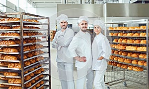 A team of bakers smiles at the bakery.