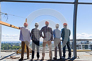 Team Of Builders On Costruction Site Back Rear View, Foreman Group In Hardhat Outdoors Partnership And Teamwork Concept